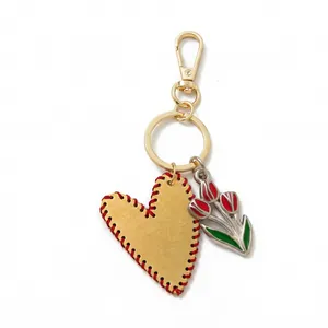 Close-up of golden heart pendant with red stitching and tulip charm keychain