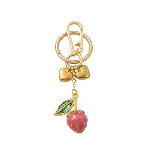 Close-up of pink strawberry charm with green rhinestones and golden heart pendants