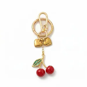 Elegant gold cherry keychain charm with red beads and green heart pendants for bags