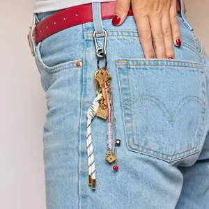 Detail of dice cherry charm with woven rope and pearl beads on a denim waist loop