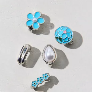Macro shot of blue enamel flower and pearl shoe charms with silver metal settings