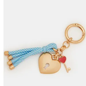 Close-up of golden heart lock keychain with blue striped tassel and red heart key charm