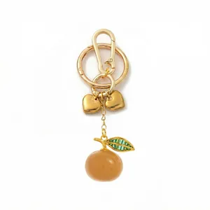 Detailed view of the gold heart charm and orange fruit pendant keychain accessory