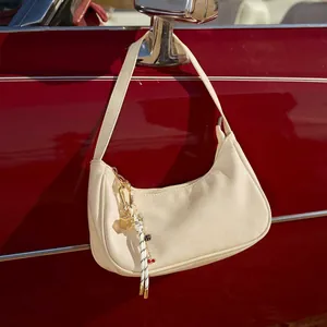 Close-up of a cream pebbled leather hobo bag with a decorative dice cherry pendant
