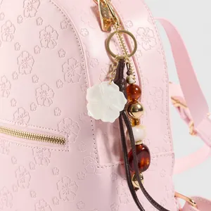 Hellrosa Rucksack mit geprägten Kirschblüten und Vintage-Perlenanhänger mit Blumendetails