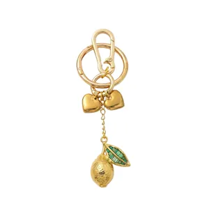 Macro view of gold lemon keychain with embossed texture and green gemstone leaf detail