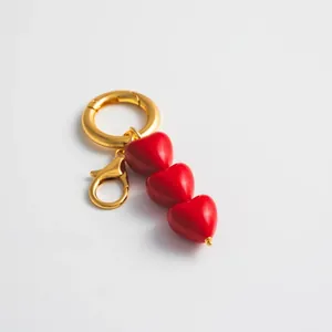 Detail of red enamel triple heart pendant with gold spring ring and lobster clasp
