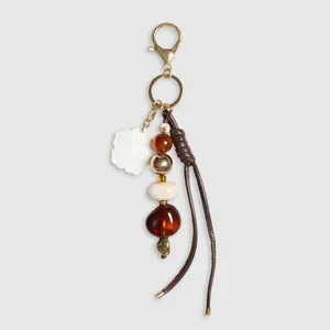 Nahaufnahme von Vintage-Perlenanhänger mit goldener Blume und braunen Lederfransen