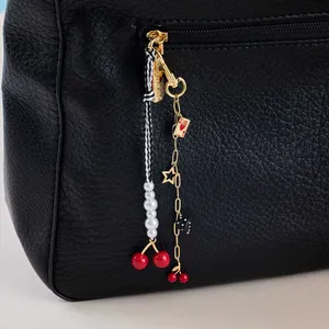 Black leather bag with cherry pearl dice pendants and gold hardware details