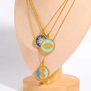 Detailed close-up of 18K gold-plated tarot pendants with celestial enamel sun and moon motifs