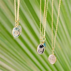 Close-up of gold oval pendants featuring snake, butterfly and flower designs on chain