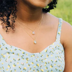 Double-layered gold necklace with pink heart and leaf stone pendants on model