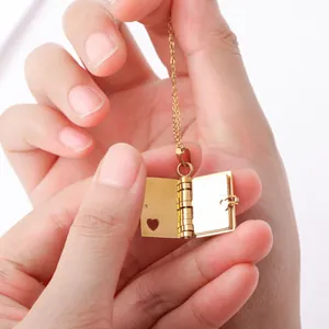 Close-up of golden book-shaped locket necklace with hollow heart and metal chain