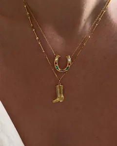 Macro detail of layered gold horseshoe and cowboy boot pendants with inlaid gemstones