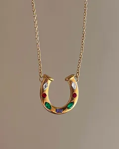 Detail view of gold horseshoe necklace with colorful inlaid crystals and cross chain