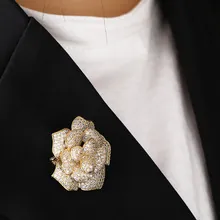 Detailed close-up of a golden rose brooch with sparkling zircons on a black blazer lapel