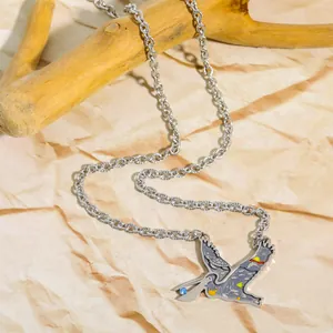 Detail of bird pendant with colorful enamel sea turtle and blue gemstone on steel chain