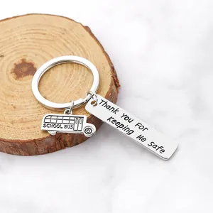 Porte-clés en acier inoxydable avec pendentif bus scolaire sur plateau en bois