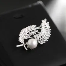 Macro shot of silver feather brooch with tapered zircons and a white pearl detail