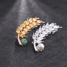 Macro detail of wheat ear brooches with sparkling zircon stones and pearl accents