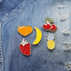 Set di spille smaltate a forma di frutta colorata su denim con fragola e ananas