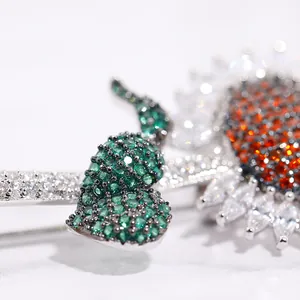 Macro view of sunflower brooch with micro-set orange and green zircons on silver base