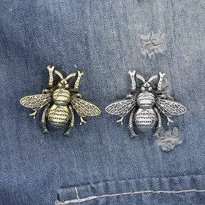 Detailopname van vintage honingbij broches van metaallegering op blauwe denim achtergrond