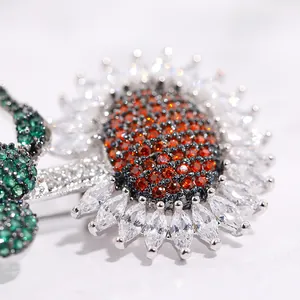 Macro detail of sunflower brooch with orange and white zircons on silver base