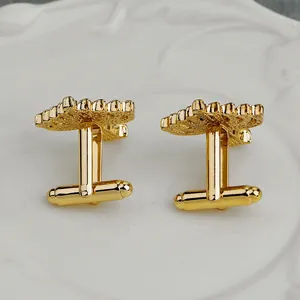 Elegant gold hollow patterned cufflinks for men's shirts on a white decorative plate