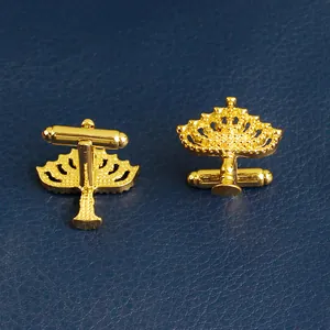 Detailed view of gold cufflinks featuring intricate hollow carvings and T-bar fastenings