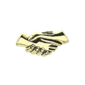 Dettaglio della spilla in metallo dorato vintage con design di mani che si stringono