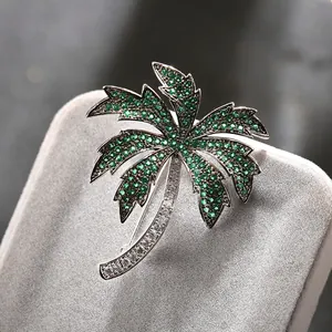 Macro view of a palm tree brooch with green crystals and a safety pin on grey velvet