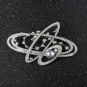 Silberne Galaxie-Brosche mit funkelnden Kristallen und blauer Perle auf schwarzem Leder