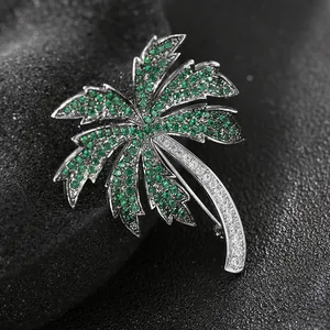 Elegant coconut tree brooch with green and white gems on a silver metal base