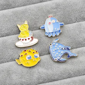 Detailed view of four colorful enamel animal pins on a gray velvet jewelry display tray