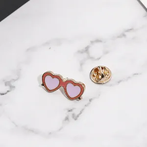 Détail du pin's émaillé en forme de lunettes de soleil coeur avec verres roses et fermoir papillon