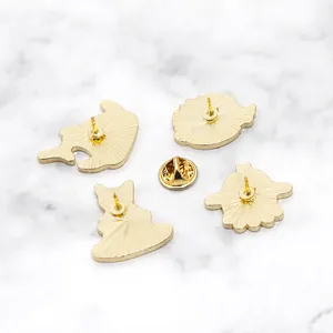 Golden enamel pin backing set with anti-slip texture and butterfly clasp on marble