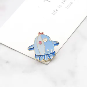Close-up of cute blue enamel whale lapel pin with pink bow and gold metal edges