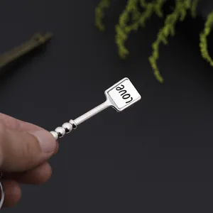 Detail showing hand-held silver alloy pendant with Love engraving and spherical accents