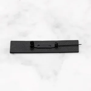 Vista de primer plano del reverso de un broche de metal negro mate con aguja y textura