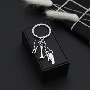 Mini metal tool keychain featuring pliers, hammer, wrench and saw charms on a gift box