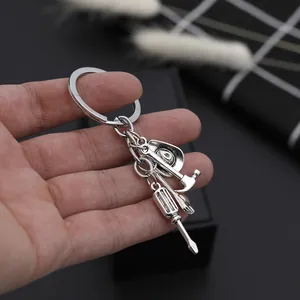 Detailed close-up of mini tool keychain charms featuring hammer and wrench held in hand