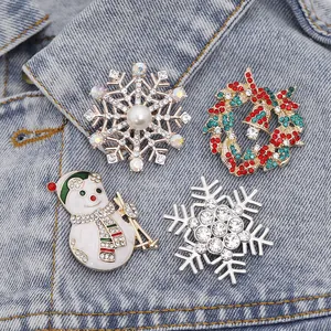 Détail de quatre broches de Noël festives avec strass sur une veste en jean