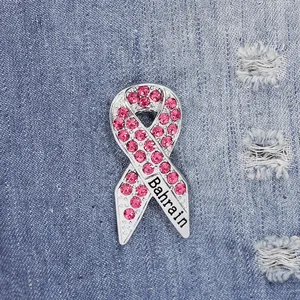 Detailansicht der rosa Schleifenbrosche mit Kristallen und Bahrain-Schriftzug auf Denim