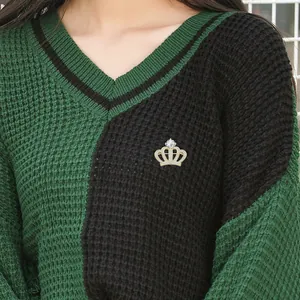 Détail d'une broche couronne dorée avec zircons épinglée sur un vêtement en maille