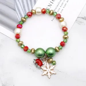 Kerst kralenarmband met bedeltjes, rode en groene glasparels op een marmeren ondergrond