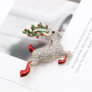 Close-up of reindeer brooch with crystal diamonds and red enamel on white paper