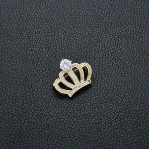 Détail d'une broche couronne dorée sertie de zircons sur fond en cuir noir