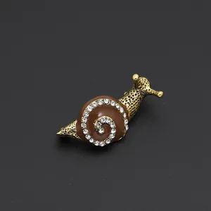 Detailed view of antique gold snail brooch with brown enamel and sparkling rhinestones