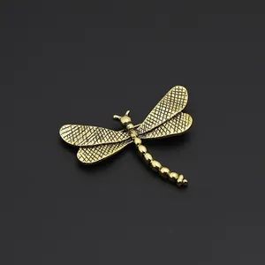 Macro view of vintage gold dragonfly brooch with detailed mesh wings on black background